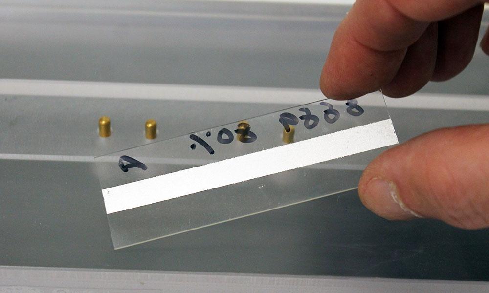 Conductive material to be tested applied to one side of a glass slide
